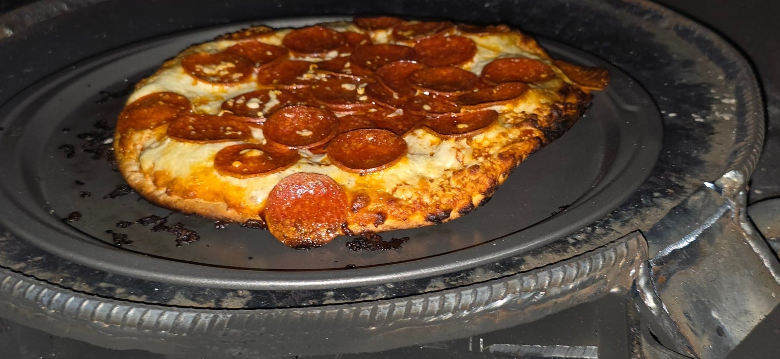 Pepperoni pizza cooked in the vertical cooking tower of the hybrid offset smoker during a shop test fire